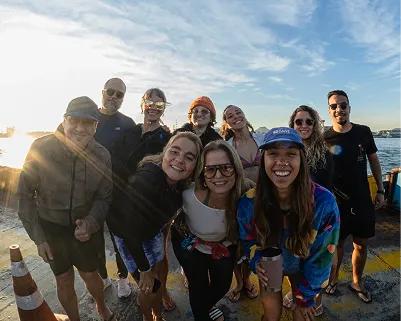 Aluna caminhando com a prancha na areia